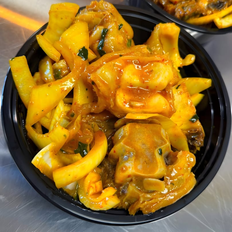 Close-up of Nigerian peppered snail and bell peppers in a black bowl.